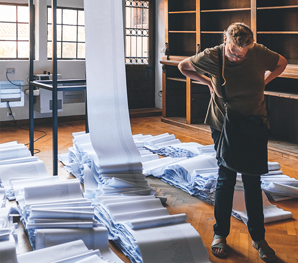 A male worker is looking at a stack of newly woven fabric in a mill