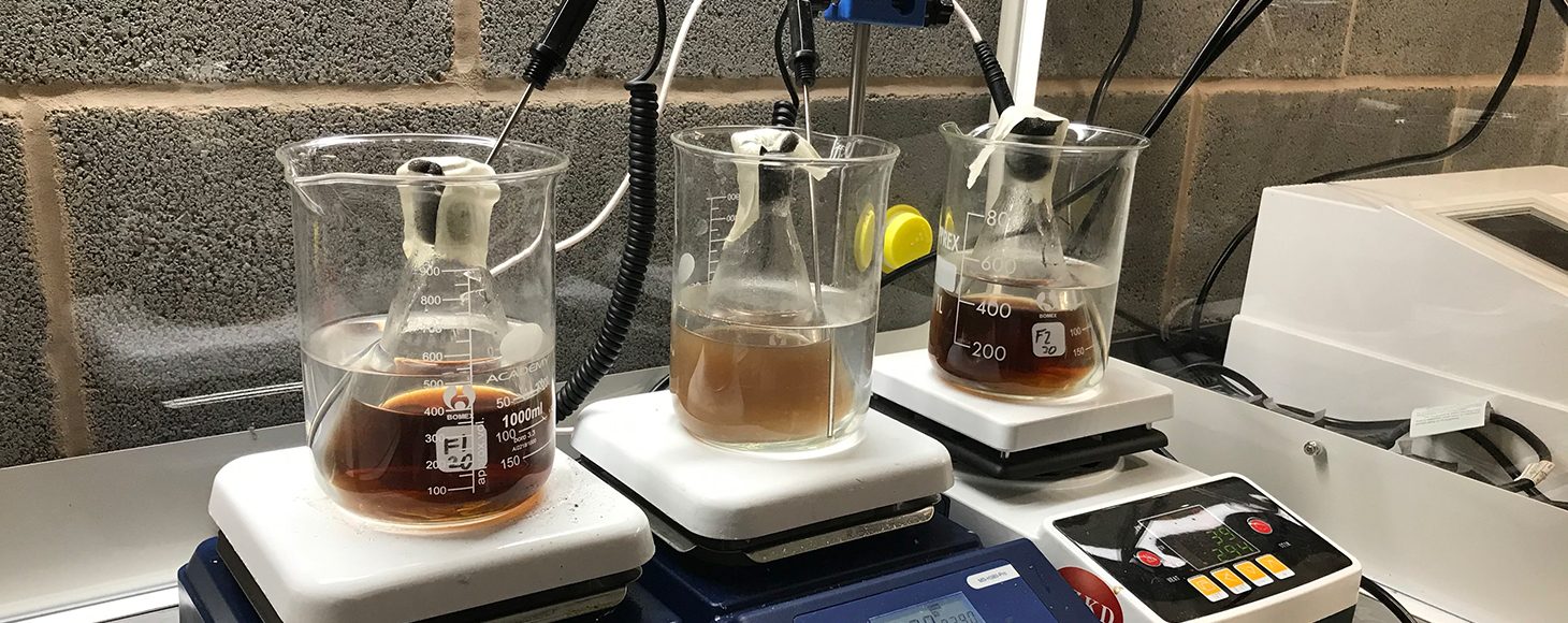 Three glass jars with brown liquid for experimental research